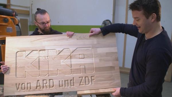 Felix und Tischlermeister Gunnar mit dem gefrästen KiKA-Logo | Rechte: KiKA