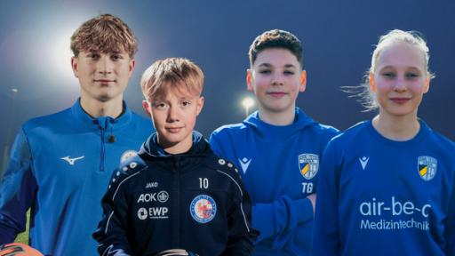 Vier Kinder in Trikots stehen im Stadion in Fußballtrikots.