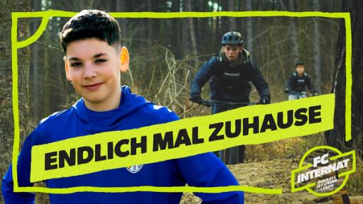 Links steht Tamiano im Trikot und lächelt. Im Hintergrund fahren zwei Kinder Mountain-Bike in einem Wald. Mittig die Aufschrift Endlich mal zuhause. Unten rechts das Logo von FC Internat.