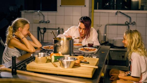 Lotte (Delphine Lohmann, links) bringt ihrer Schwester Luise (Mia Lohmann) Kochgerichte bei. Koch Matteo (Vincent Sauer) hilft ihnen dabei. | Rechte: SWR/Uschi Reich