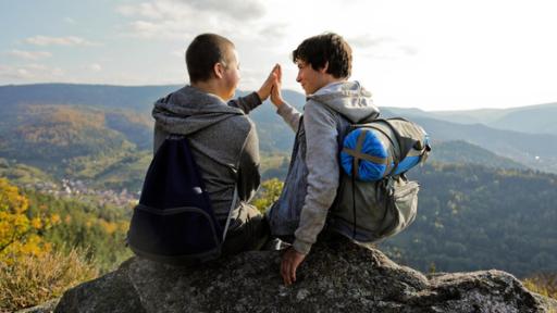 Zwei Jungen sitzen auf einem Felsen und klatschen sich ab