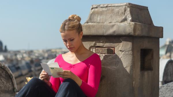 Lena (Jessica Lord) sitzt an ihrem Lieblingsplatz auf dem Dach der Oper in Paris und liest den Abschiedsbrief von Max, der die Ballettschule überraschend verlassen hat. Sie versteht nicht, wieso er sich nicht persönlich von ihr verabschiedet hat. | Rechte: ZDF/Nicolas Velter
