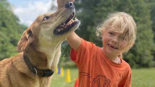 Milan mit seinem Hund Simba auf einer Wiese.