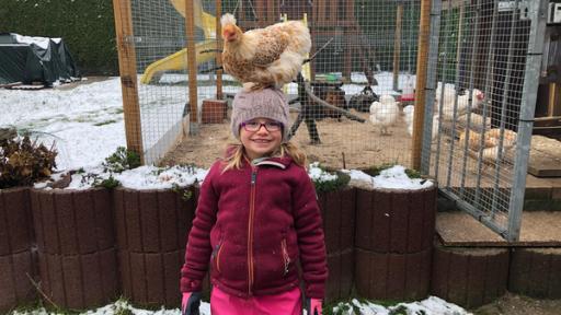 Lina mit einem Huhn auf dem Kopf