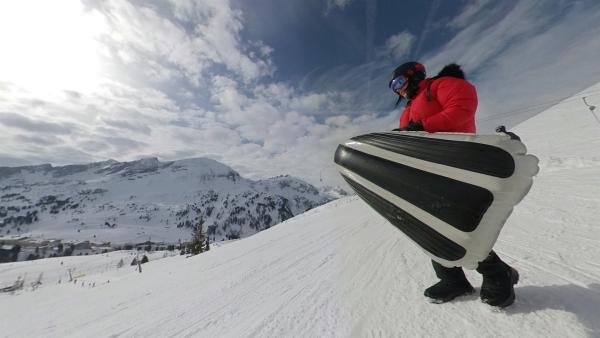 Jess probiert am Skihang eines der Wintersportgeräte. | Rechte: KiKA/Torben Hagenau