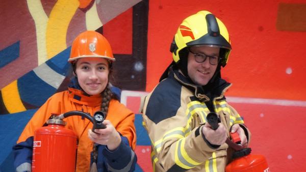 Ben besucht die Feuerwehrerlebniswelt in Augsburg. Dort zeigt ihm Feuerwehrmitglied Emilia, welche Eigenschaften ein Feuerwehrmann haben sollte, um Brände oder andere Katastrophen bekämpfen und Menschen helfen zu können. | Rechte: KiKA/Franziska Gruber