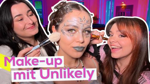 In der Mitte Sarahs Gesicht mit Make-up im Metallic-Look. Links und rechts neben ihr Ally und Laura. Sie halten Pinsel in der Hand und bepinseln damit Sarahs Gesicht. Unten die Aufschrift: Make-up mit Unlikely.