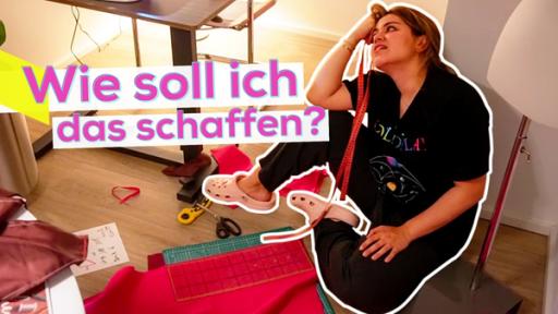 Sarah sitzt auf dem Boden an die Wand gelehnt. Sie sieht geschafft und etwas verzweifelt aus. Auf dem Boden rund um sie herum liegen roter Stoff und Stoffreste, eine Schneidmatte, eine Schere und Skizzen. Im Hintergrund angeschnitten eine Schneiderpuppe und ein Tisch mit einer Nähmaschine. Aufschrift obere, linke Bildhälfte: Wie soll ich das schaffen?