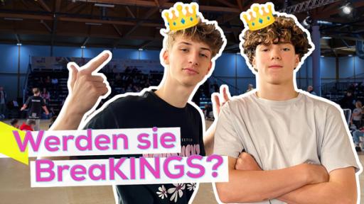 Die Breakdancer Ian und Lasse stehen mit lässig-coolen Posen und einem Kronen-Emoji auf dem Kopf beieinander. Im Hintergrund Publikum und die gefüllte Tanzfläche in der Messehalle in Magdeburg. Aufschrift: Werden sie BreaKINGS?