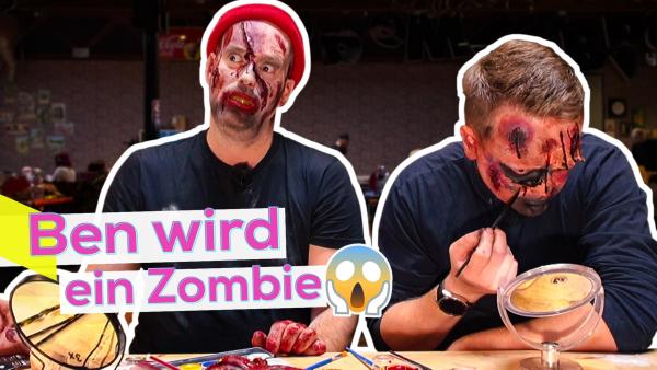 Ben und Marvin sitzen an einem Schminktisch mit Utensilien. Beide haben Kunstblut und falsche Wunden im Gesicht und arbeiten an ihrem Zombie-Make-up. Ben übt seine Mimik als Monster. Aufschrift unten links: Ben wird ein Zombie. Daneben ein Angst-Emoji.