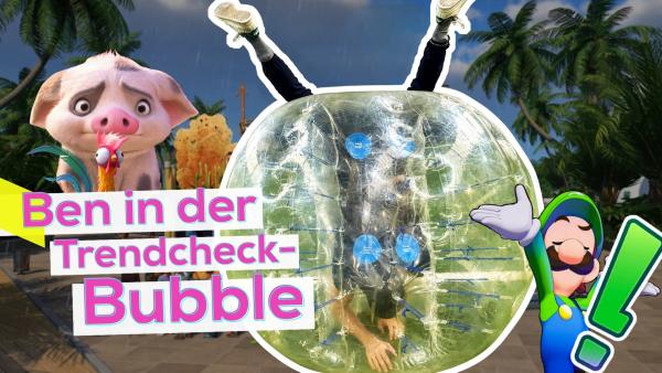 Ben steckt kopfüber in einem Bubbel-Ball. Seine Beine ragen unterhalb der Knie oben aus der Kugelöffnung. Links ein animiertes Schwein und ein Hahn aus dem Film Vaiana. Rechts der Nintendo-Charakter Luigi. Im Hintergrund das Setting aus dem Spiel Planet Coaster. Aufschrift: Ben in der Trendcheck-Bubble.