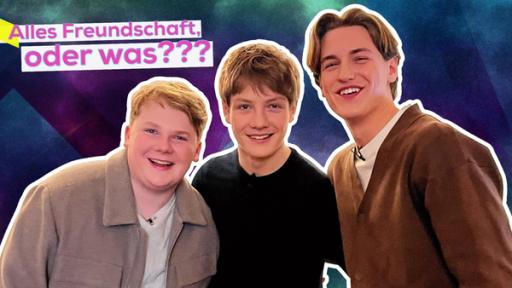 Julius Weckauf, Levi Brandl und Nevio Wendt stehen eng nebeneinander und lächeln. Text oben links: Alles Freundschaft, oder was???