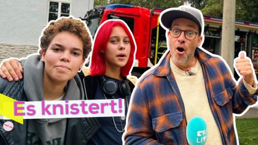 Rechte: KiKA/Andrea Thoben Ava und Elly eng nebeneinander, daneben Ben, der erstaunt mit dem Daumen hinter sich zeigt. Im Hintergrund ein Feuerwehrauto. Aufschrift: Es knistert!