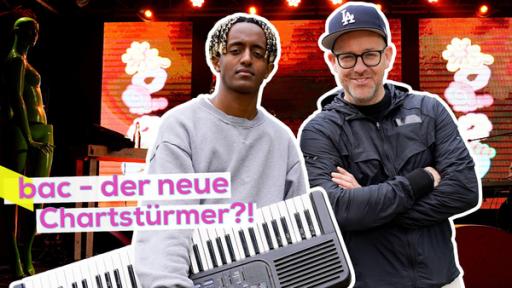 Musiker Samuel aka bac mit Keyboard unterm Arm vor seiner Bühne in Köln. Eng neben ihm Ben gut gelaunt. Aufschrift: bac - der neue Chartstürmer?!