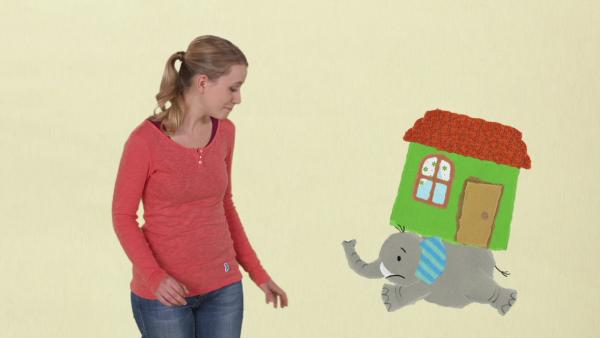 Anni schaut dem Elefanten zu, der ein Haus auf dem Rücken trägt