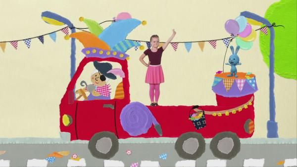 Ein Mädchen tanzt als Funkenmariechen mit Kikaninchen auf einem Umzugswagen.