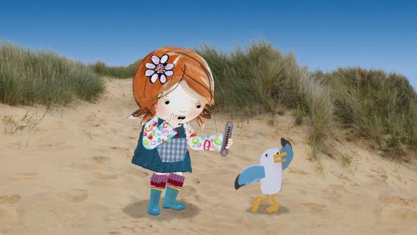 Lily überlegt, was man auf der Mundharmonika, die sie am Strand gefunden hat, alles spielen kann. | Rechte: KiKA/Sixteen South
