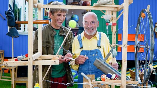 Fritz Fuchs und Peter Lustig stehen an einer Erfindung und lachen. | Rechte: ZDF