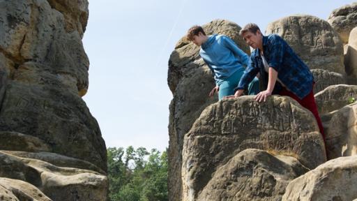 Fritz und Bruno stehen auf einem Felsen und beugen sich über den Abgrund