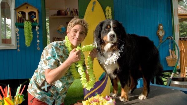 Fritz trägt eine Hawaii-Blumenkette und ist dabei Keks auch eine Kette umzulegen. | Rechte: ZDF