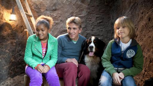 Fritz Fuchs, Milly, Victor und Keks stehen vor einer Baustelle am Bauwagen.