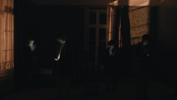 Von links: Leonie (Lea Drinda), David (Johan Korte), Elif (Safinaz Sattar) und Yussuf (Shadi Eck) stehen im dunklen leeren Zimmer mit ihren Handys in der Hand. | Rechte: BR/TV60Filmproduktion GmbH/Ralf K. Dobrick