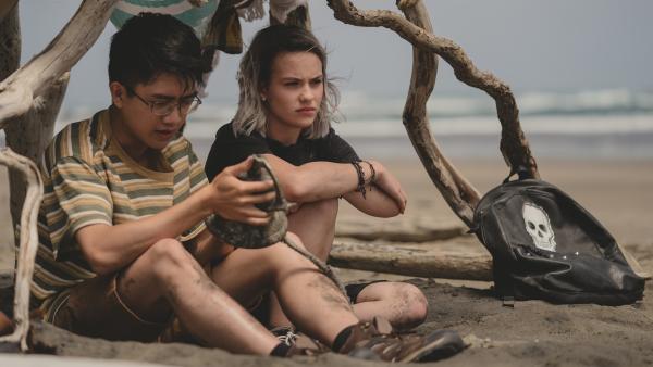 Caleb (Joshua Tan, l.) hat eine alte vergrabene Schiffsglocke am Strand entdeckt, nachdem er Issie (Macey Chipping, r.) offenbart hat,  dass er homosexuell ist. | Rechte: ZDF/Matt Klitscher