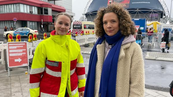 Helferin Johanne Stümpel erzählt Reporterin Gesa, wie sie die Geflüchteten in der Kölner Anlaufstelle in Empfang nimmt. | Rechte: WDR/tvision