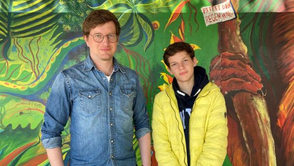 Robert und Jannis stehen vor einer bunt angemalten Wand in Jannis' Schule. | Rechte: WDR | tvision