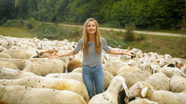 Jana steht mit ausgebreiteten Armen in einer Schafherde | Rechte: WDR