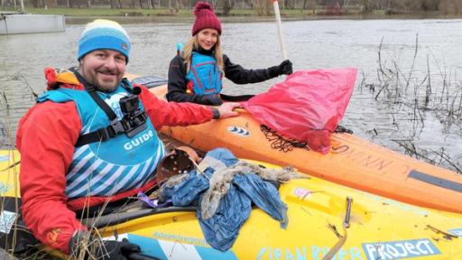 Jana und Stephan sitzen in einem Kanu auf der Mosel. Auf ihren Kanus liegt Müll, den sie gesammelt haben.