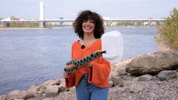 Reporterin Tessniem steht am Rheinufer mit einem Müllgreifer, der aussieht wie ein Tentakel. | Rechte: WDR/tvision