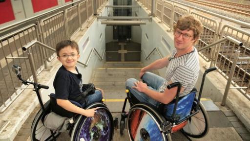 Robert und Timon in Rollstühlen vor einer Treppe