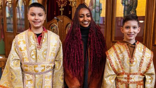 Luam steht zwischen Georgios (links) und Dimitrios (rechts) vor einer griechisch-orthodoxen Ikonostase. Die beiden Jungen tragen Altardiener-Gewänder.