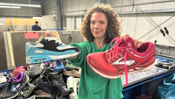 Reporterin Gesa steht in einem Textilsortierunternehmen und hält zwei Paar Sneaker in die Kamera. | Rechte: WDR | tvision