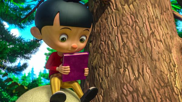 Pinocchio sitzt neben einem Baum auf einem Stein und schaut ein Buch an, das er in den Händen hält. | Rechte:  © 2021 - Method Animation - Palomar - ZDF - ZDF Enterprises