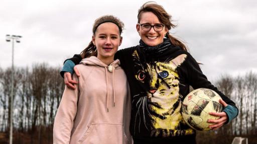 Die Princess of Science Johanna (re.) steht neben einer Sportlerin (li.) in der Sporthalle. In den Händen halten sie Stäbe für den Stabhochsprung.