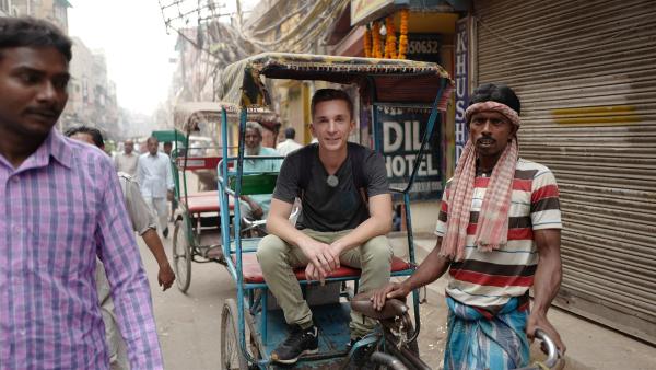 "pur+"-Moderator Eric Mayer (M.) in einer Fahrradrikscha unterwegs in Delhi. Delhi gehört zu den wenigen Städten, in denen es noch Fahrradrikschas gibt. Fast überall haben Rikschas inzwischen einen Motor. Aber in Alt Dehli sind die Gassen so eng, dass dort nur schmale Fahrradrikschas durch kommen. | Rechte: ZDF/Zeljko Pehar