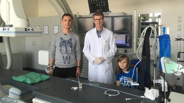 Die elfjährige Sarai (r.) hat einen Herzfehler. Prof. Dr. med. Peter Ewert (M.) erklärt ihr und "pur+"-Moderator Eric Mayer, wie er ihr eine neue Herzklappe einsetzen wird. | Rechte: ZDF/Dirk Beppler
