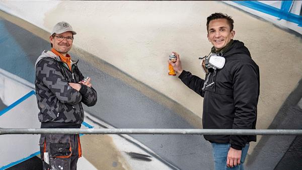 "PUR+"-Moderator Eric Mayer versucht sich im sprayen. Er begleitet den bekannten Streetart-Künstler DAIM bei der Gestaltung eines riesigen Graffitis. Wie kriegen sie den 3D-Effekt auf die flache Wand? | Rechte: ZDF/Nika Kramer
