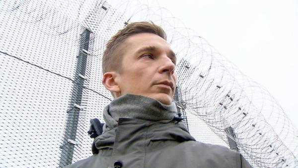 Eric steht vor einem Stachedrahtzaun | Rechte: ZDF