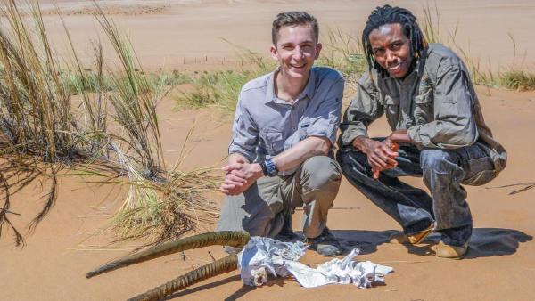 Eric kniet mit Titus in der Wüste hinter dem Schädel eines Tiers. | Rechte: ZDF