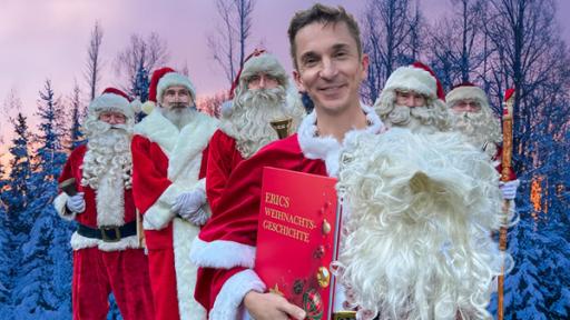 Moderator Eric Mayer steht, als Weihnachtsmann verkleidet, im Kreise weiterer Weihnachtsmänner im Freien. Er hält ein rotes Buch mit der Aufschrift "Erics Weihnachtsgeschichte" in der rechten Hand. Im Hintergrund sind verschneite Tannnen zu sehen, hinter denen die untergehende Sonne den Himmel in orangene und lila Farbverläufe taucht.