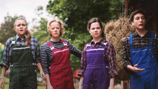 Am Stall stehen Nele, Martha, Sarah und Kasimir in bunten Latzhosen und schauen verwundert.