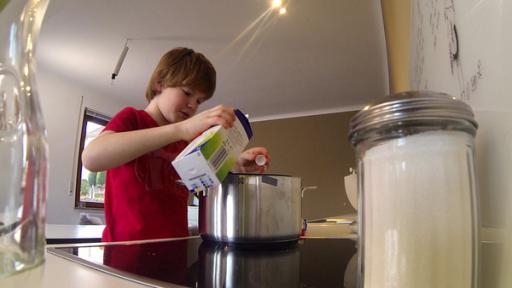 Nik schüttet Milch in einen Topf um Milchreis zu kochen.