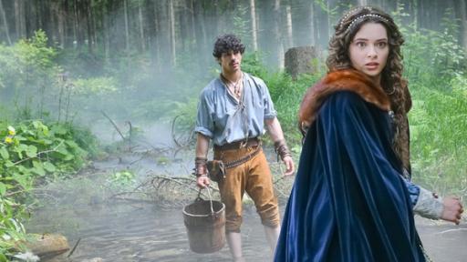 Tagsüber im Wald: Verängstigt dreht sich Julia (Katarína Krajčovičová) um. Sie trägt einen dunkelblauen Umhang mit braunem Pelzkragen. In ihren dunklen, langen Haaren sind Perlen eingearbeitet. Im Hintergrund steht Juraj (Ladislav Bédi) barfuß mit einem Holzeimer in einem Bach. Im Hintergrund steigen Nebelschwaden im Wald auf.