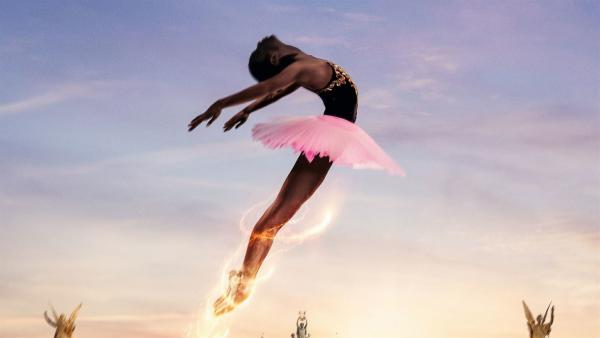 Eine Ballettänzerin in der Luft. Im Hintergrund eine barocke Hausfront. Darüber blauer Abendhimmel.