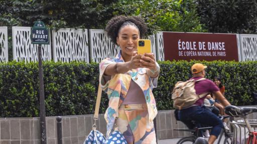 Cece steht mit ihrem Handy vor der Ballettschule der Pariser Oper und macht ein Selfie.