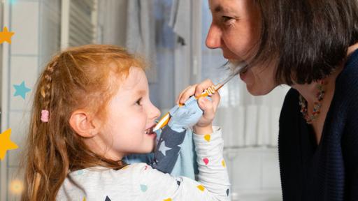 Karolina putzt ihrer Mama die Zähne.