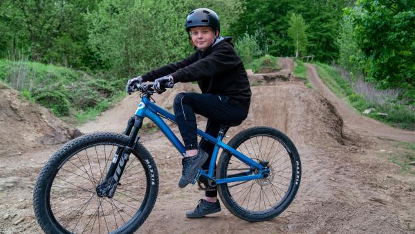Mika ist am liebsten im Freien unterwegs und sein Hobby ist Dirt Bike. Auf einem Parcours mitten im Wald springt der Elfjährige mit seinem Fahrrad über Rampen aus Erde. | Rechte: ZDF/Florian Lippke